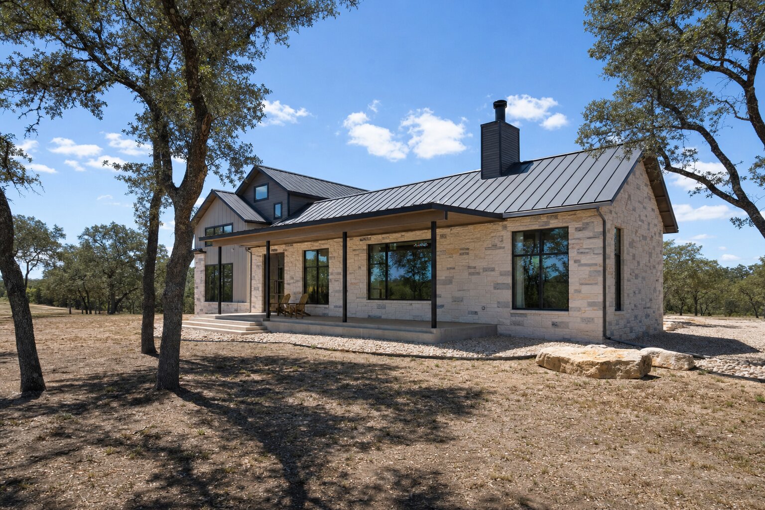 Hill Country custom home built to resist wildfire with a metal roof, stone siding, and a gravel hardscape buffer